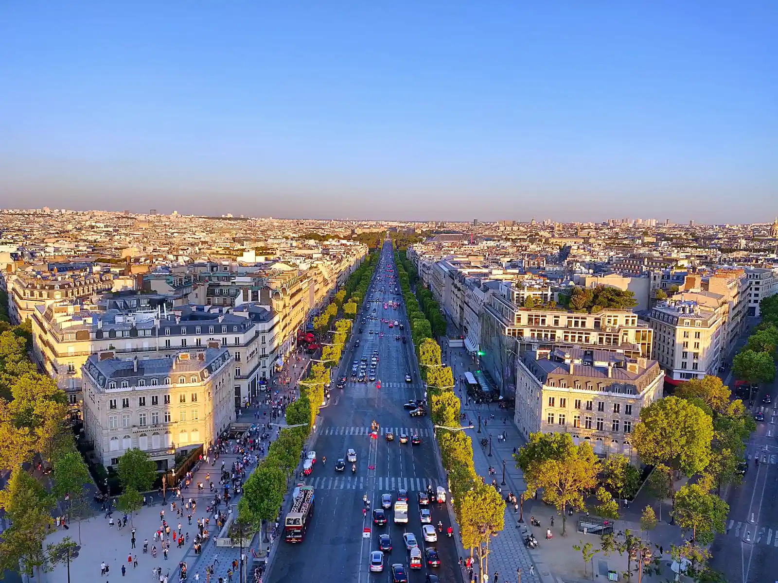 Champs-Élysées avenue lined with trees leading toward the Arc de Triomphe in Paris