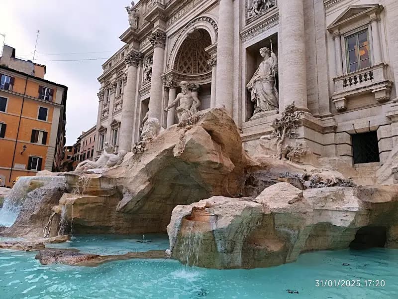 Trevi Fountain in Rome lit up in the evening with crowds gathered nearby