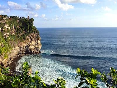 Uluwatu temple on cliff edge overlooking Bali ocean at sunset