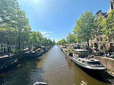Locals cycling along a quiet canal in Amsterdam's Jordaan, an offbeat local neighbourhood spot