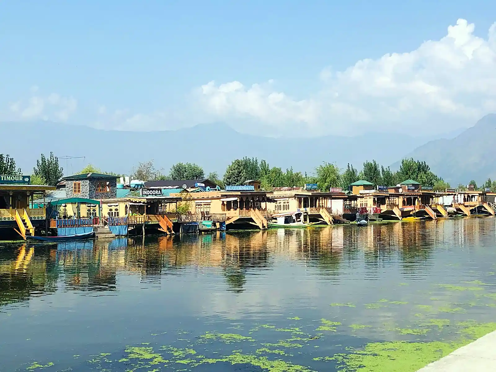 Wooden houseboats moored on Dal Lake in Kashmir with surrounding mountains at dawn