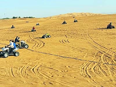 Camels and travellers lined up on Dubai desert dunes at golden hour before an evening safari camp dinner