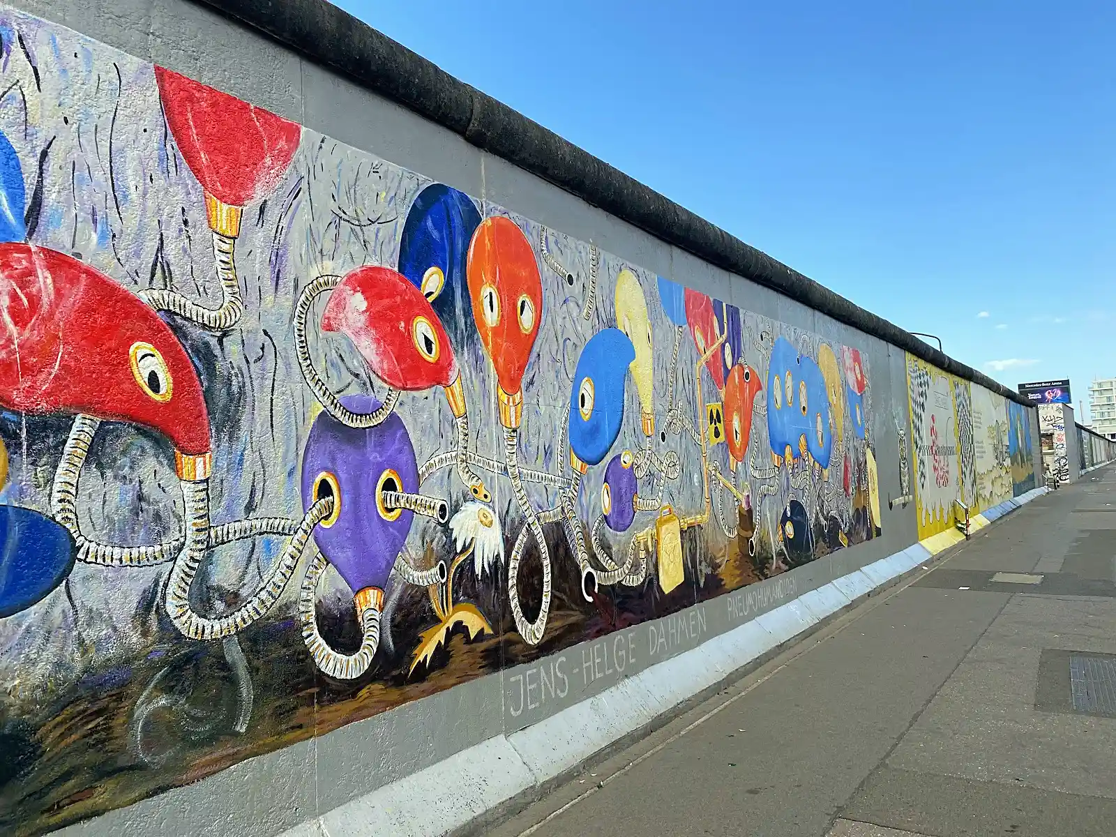 Cyclists riding past the mural covered East Side Gallery, an offbeat Berlin local spot